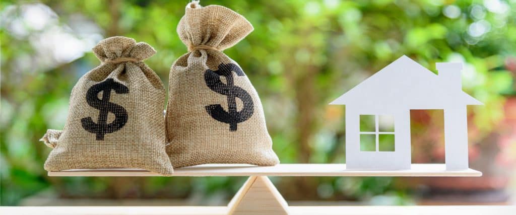A scale with money on one side and a paper house on the other.