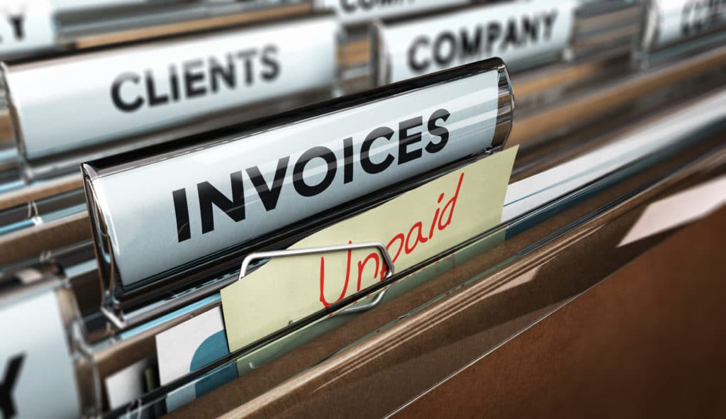Close up on a file tab with the word invoice and a note where it is handwritten unpaid with blur effect. Concept image for illustration of unpaid invoices recovery.