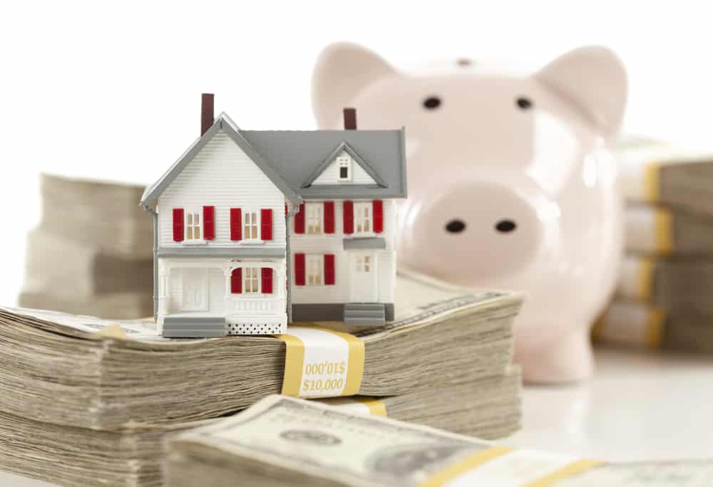 Small House and Piggy Bank with Stacks of Hundred Dollar Bills Isolated on a White Background.