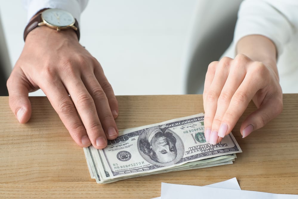 A male and a female hand resting on a pile of money