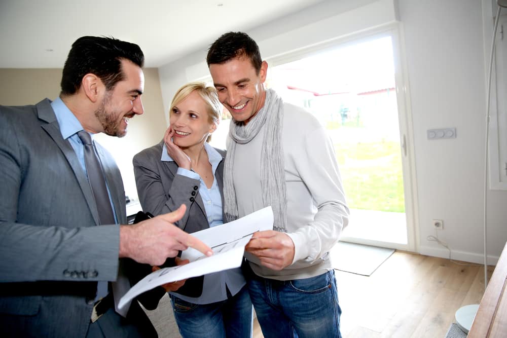 Middle-aged couple visiting house with salesman
